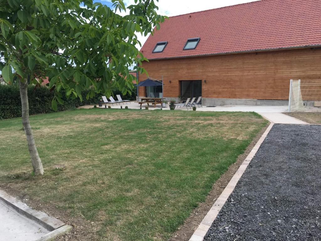 HermelinghenCharmant gîte à la ferme situé à 20 min de la mer的一个带野餐桌的庭院和一座建筑