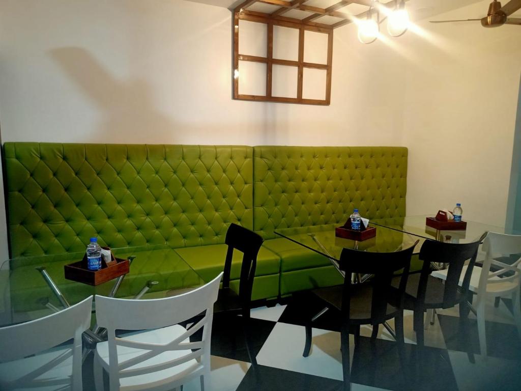 古瓦哈提VIAN INN的一间带绿色沙发和桌子的用餐室
