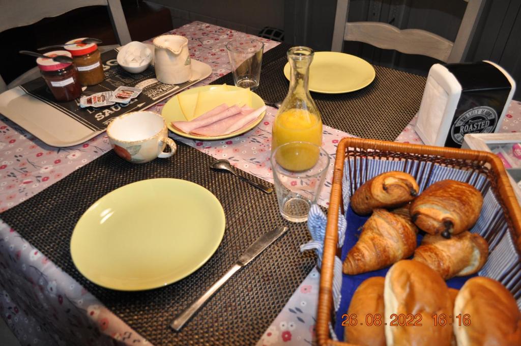 特镇Bon séjour的一张桌子,上面放有盘子和羊角面包,还有一篮面包