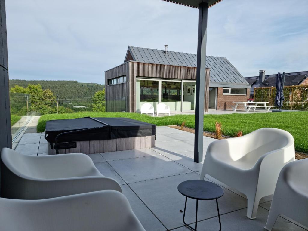 弗朗科尔尚Le Lièvre Debout Francorchamps - spa et sauna的庭院配有白色椅子和台球桌