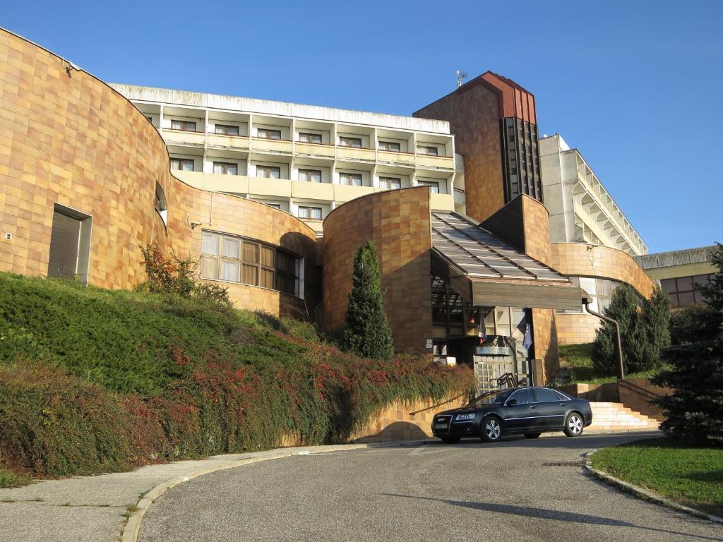 布拉迪斯拉发Retro Hotel Suza的停在大楼前的路上的汽车