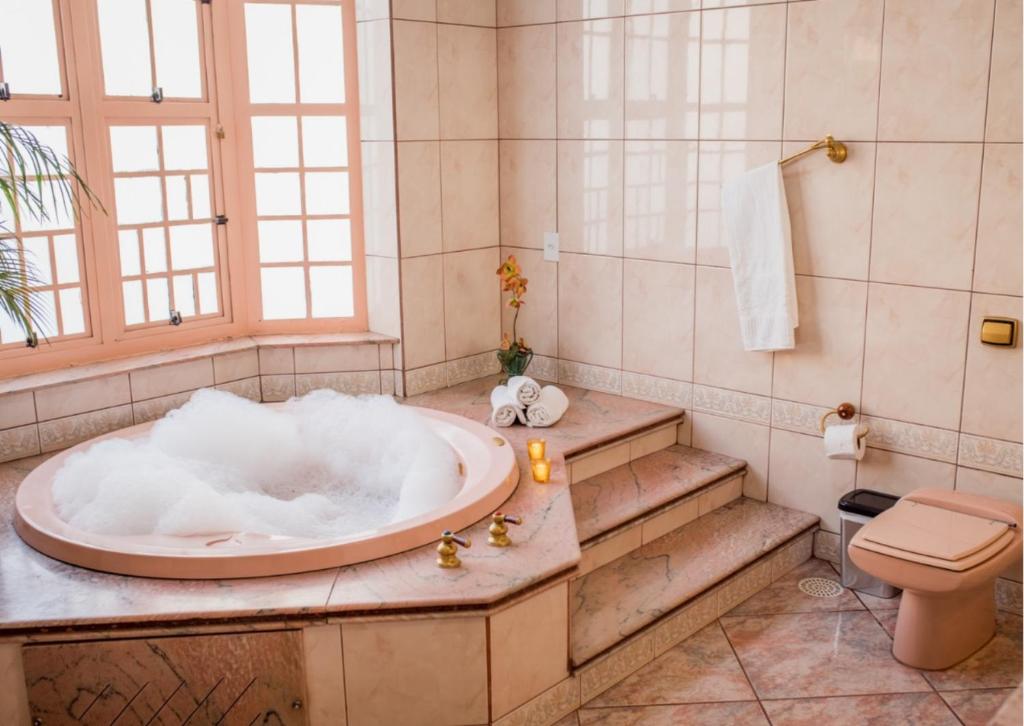 阿帕雷西达Rogai Hotel Pousada的带浴缸和卫生间的浴室。