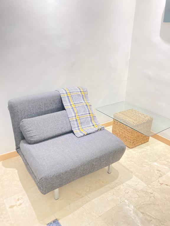 加拉加斯HATILLO SUITE的玻璃桌旁的灰色沙发,上面有毯子