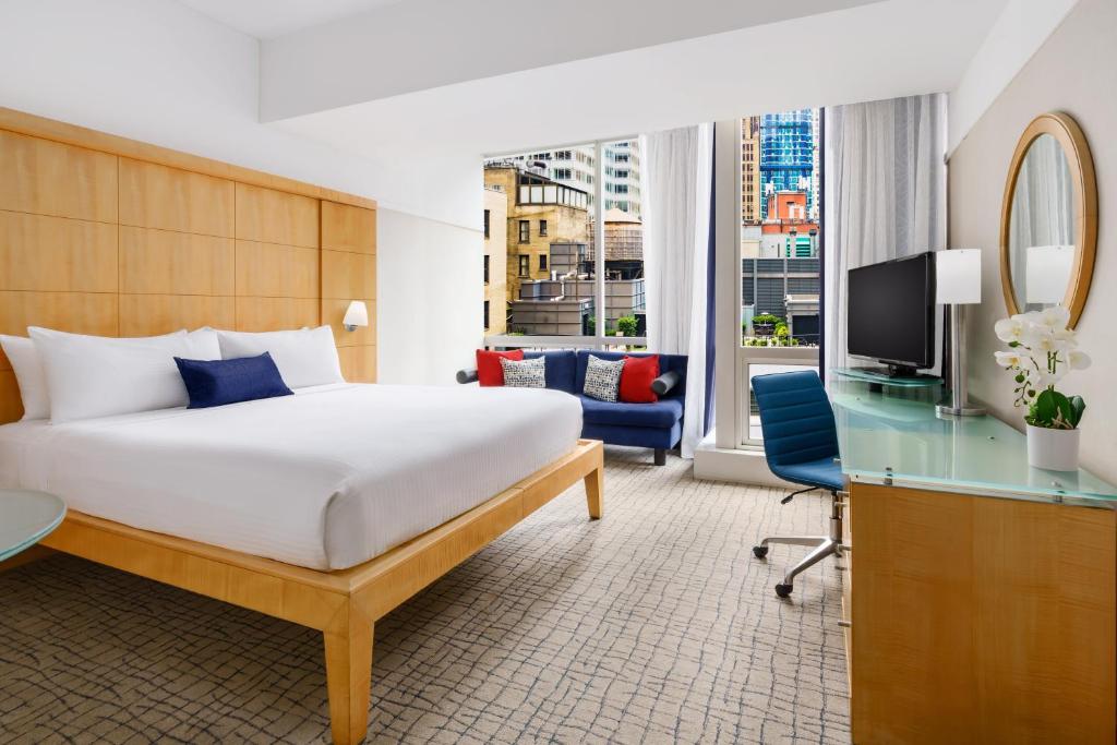 纽约千禧纽约时代广场酒店的一间卧室配有一张床、一张书桌和一台电视。