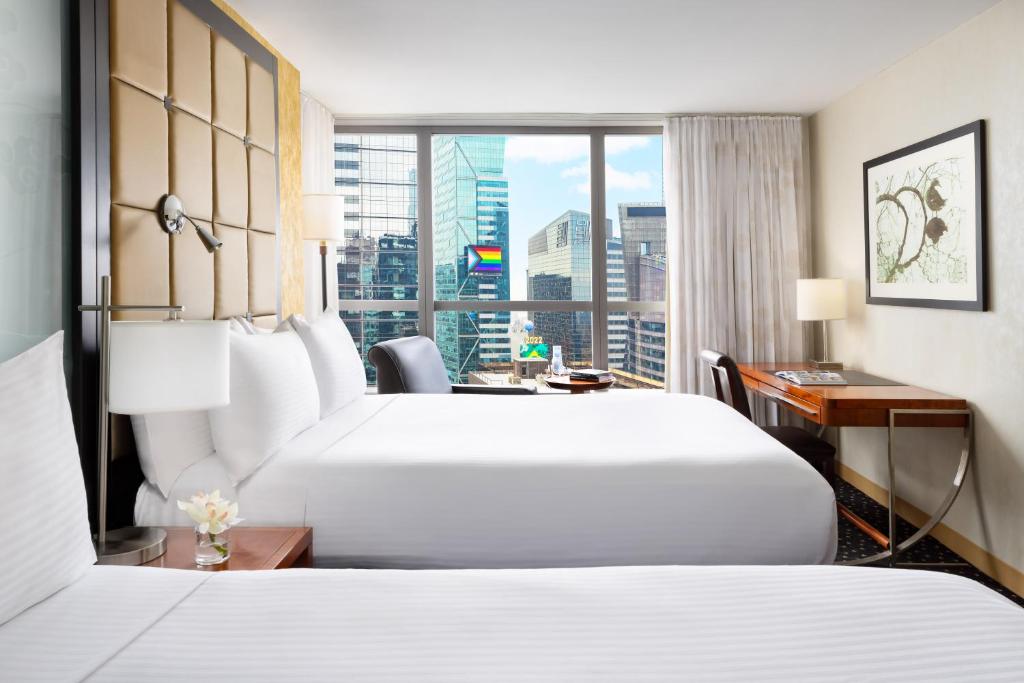 纽约Millennium Hotel Broadway Times Square的酒店客房设有两张床、一张书桌和一个窗户。