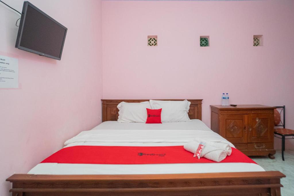 巴图RedDoorz Syariah near Batu Night Spectacular 3的卧室配有一张床铺,墙上配有电视