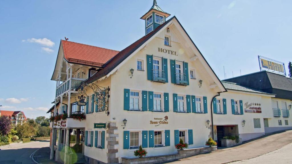 菲希特瑙Meiser Rosenstuben Hotel的一条白色的大建筑,在街上有蓝色百叶窗