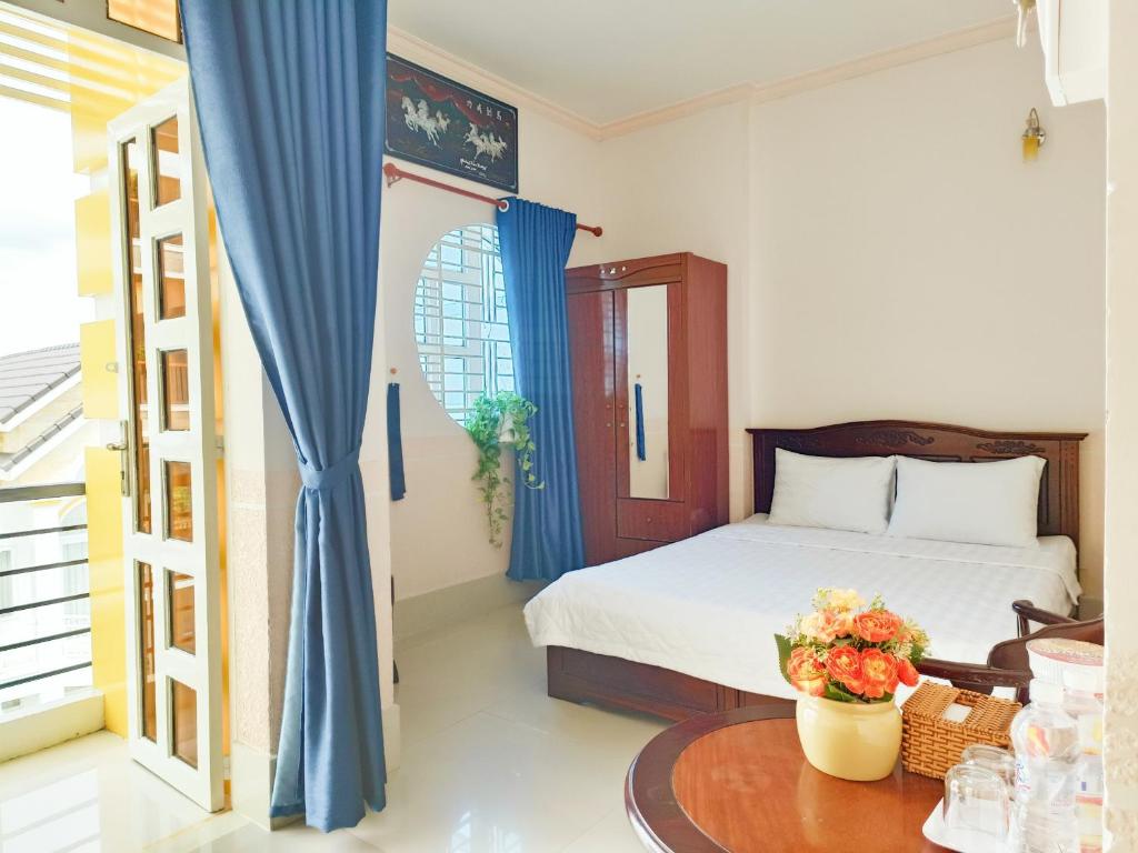 芹苴NAMA HOTEL - Ninh Kieu Center的一间卧室配有一张带蓝色窗帘的床和一张桌子