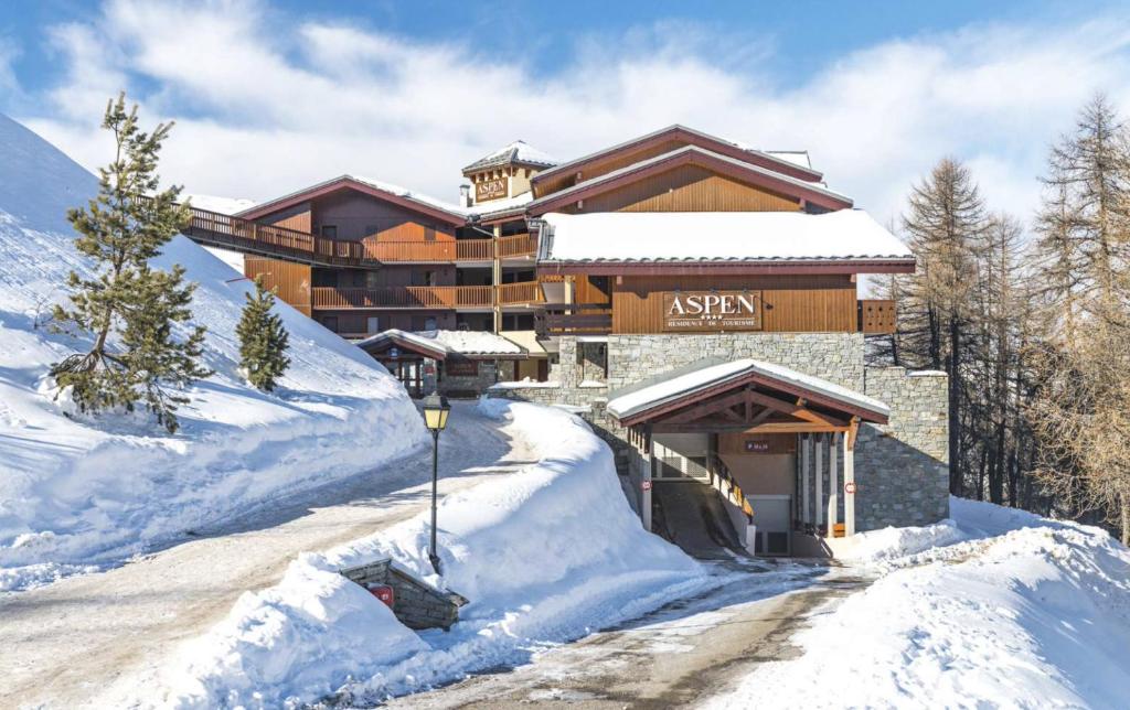 普拉涅村Plagne Villages, Charmante Résidence de Tourisme 4 Etoiles的雪地中的滑雪小屋,有雪覆盖的道路