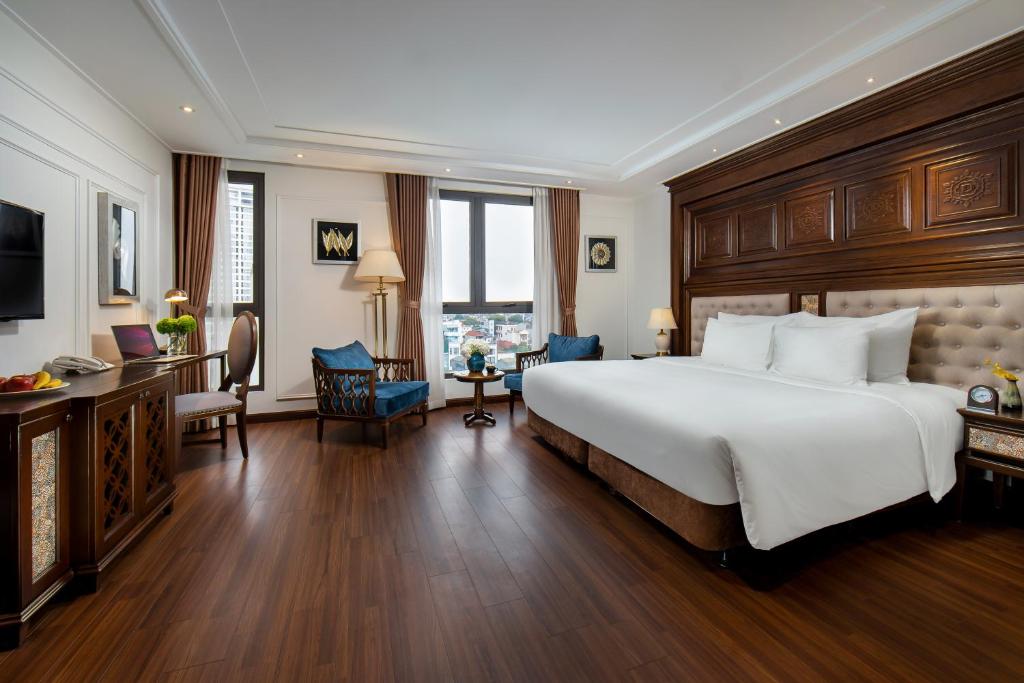 河内The Q Hotel的酒店客房设有一张大床和一张书桌。