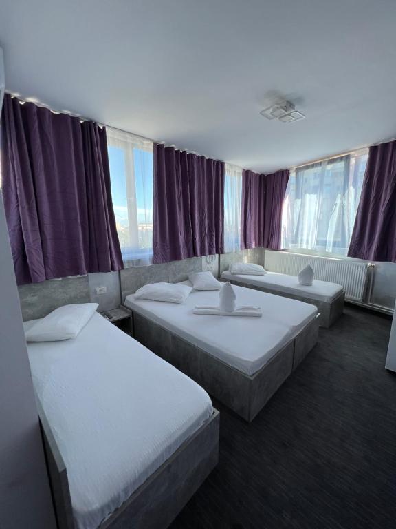 康斯坦察Hotel AMA WORLD的酒店客房设有三张床和紫色窗帘