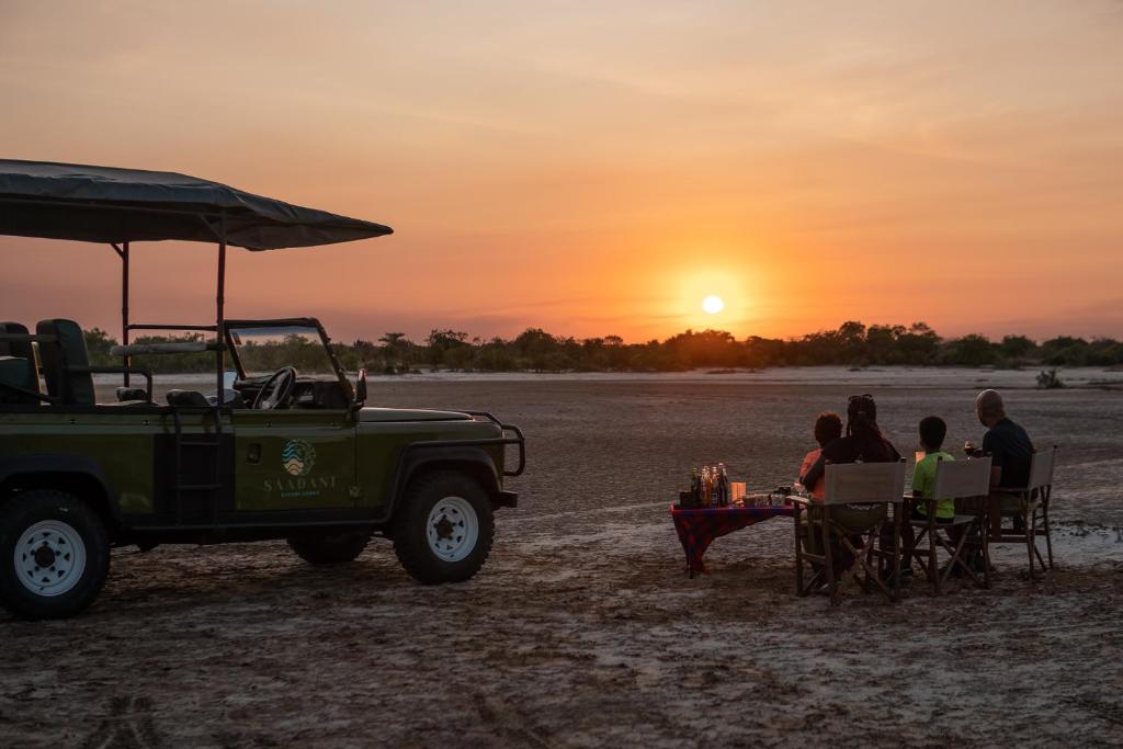 SaadaniSaadani Safari Lodge的一群坐在桌子旁观看日落的人