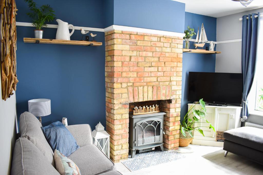 PakefieldSeagull Cottage - Suffolk Coastal Escapes的客厅设有砖砌壁炉和电视。