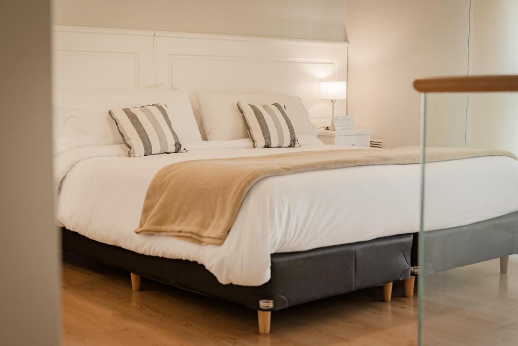 罗萨里奥Carat Apart Boutique的一张配有白色床单和枕头的大床