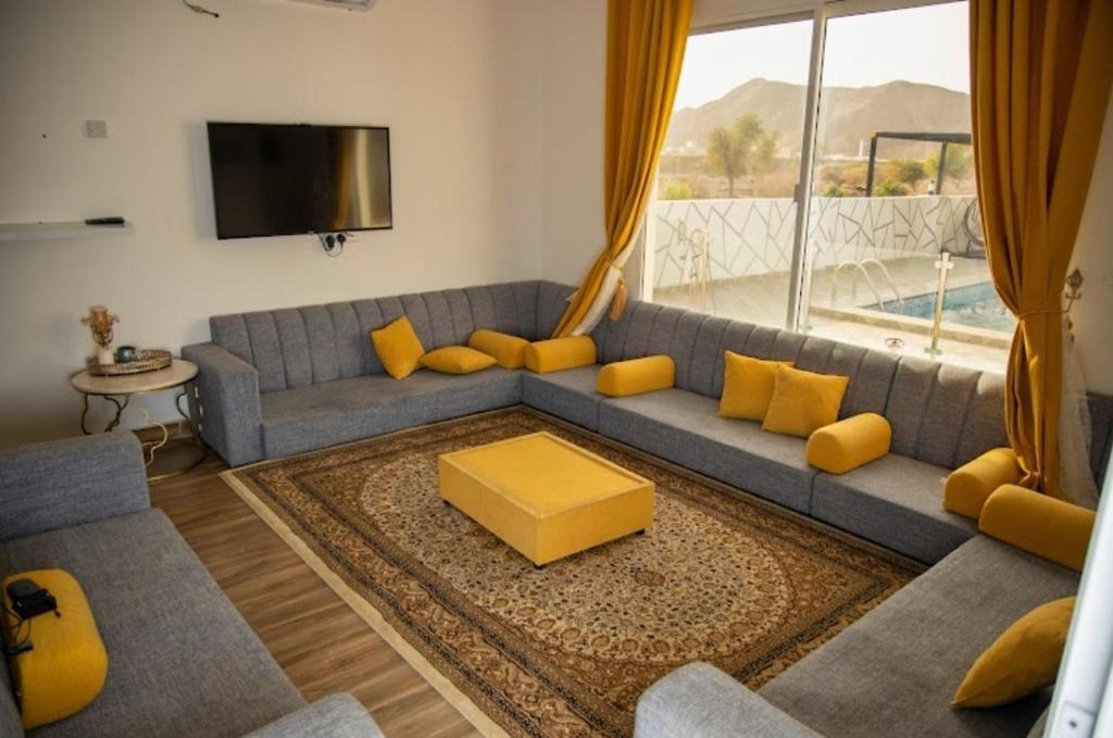 DawwahWadi Bani Khalid - Al Joud Green Hostel的客厅配有蓝色的沙发和黄色的枕头。