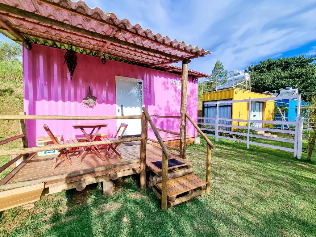 伊塔佩瓦Pousada Recanto dos Bentos的粉红色的房子,甲板上配有桌椅