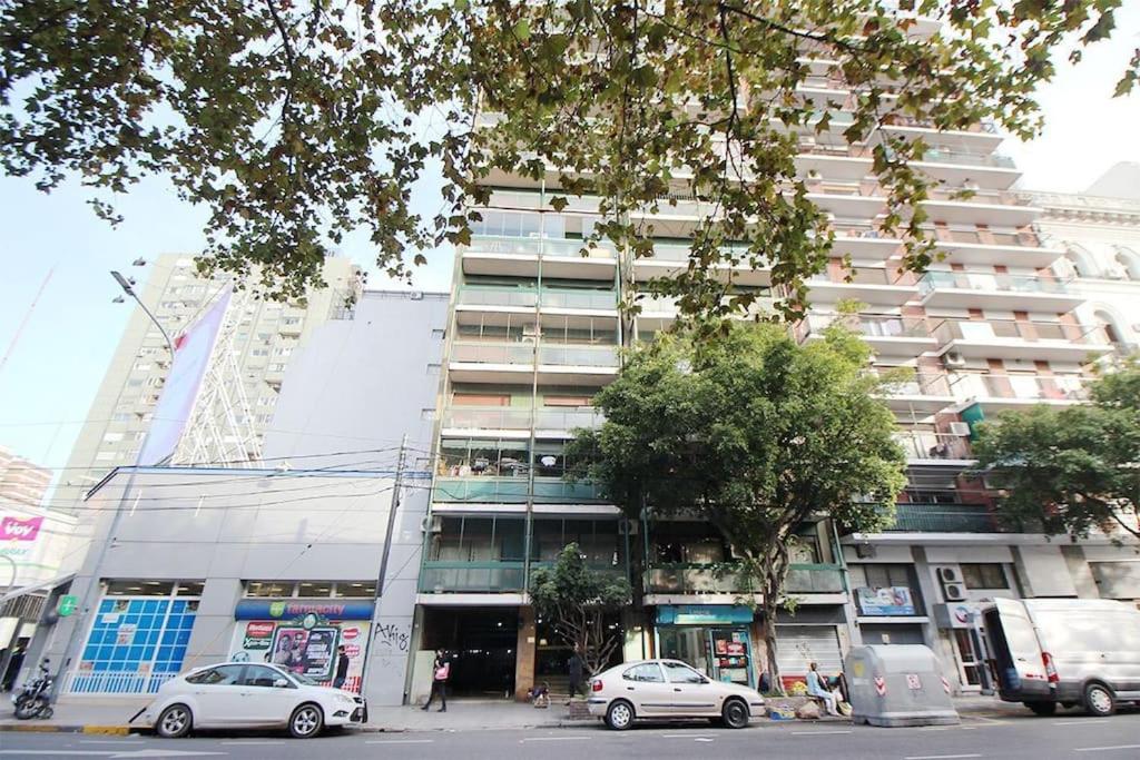 布宜诺斯艾利斯Departamento muy buena ubicacion的一座高大的建筑,前面有汽车停放