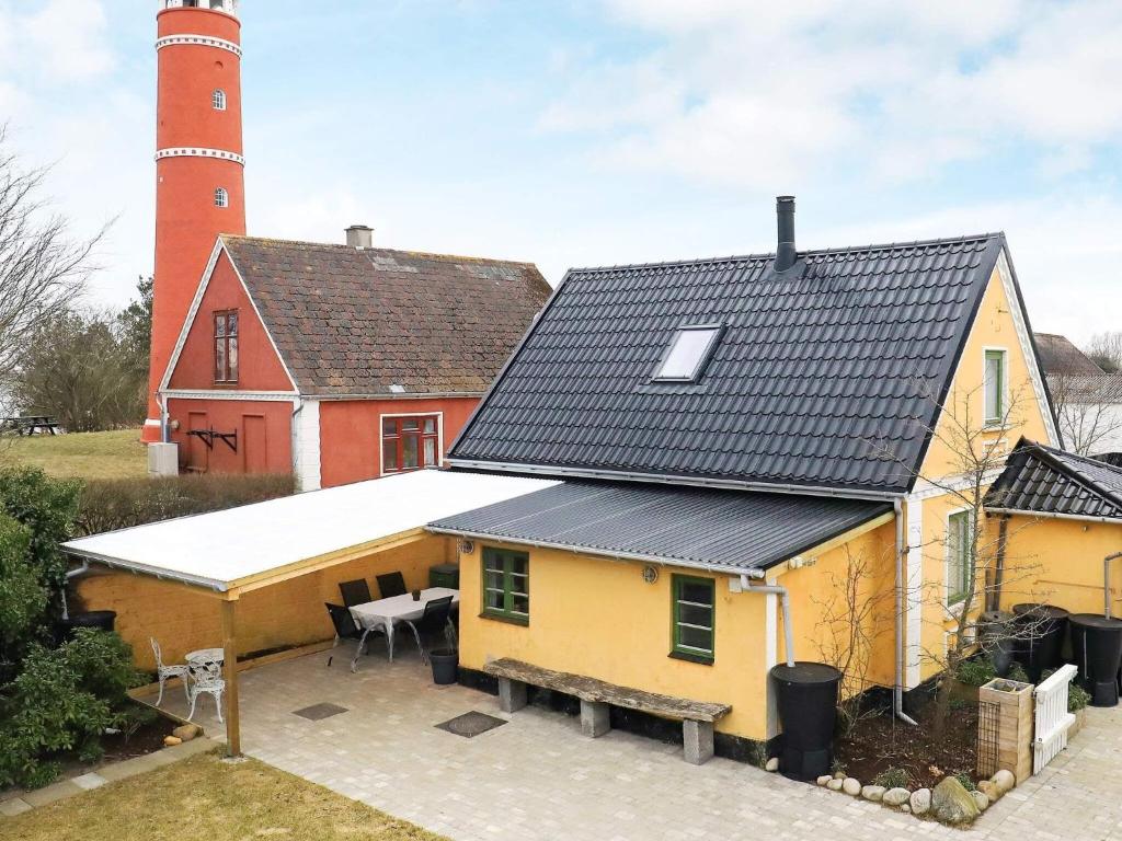 莱斯Holiday home Læsø XLI的黄色房子,后面有灯塔