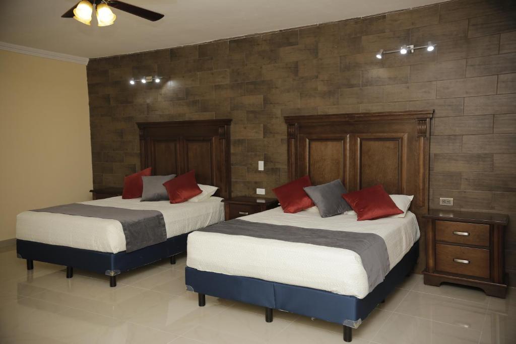 SabinasHotel Posada Santa Fe的一间卧室配有两张带红色枕头的床
