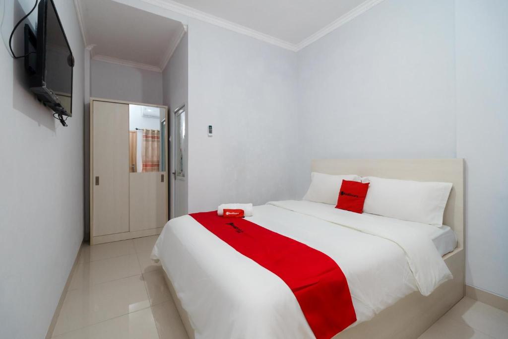 明古鲁省RedDoorz Syariah near Universitas Bengkulu的一间白色卧室,床上铺有红色毯子