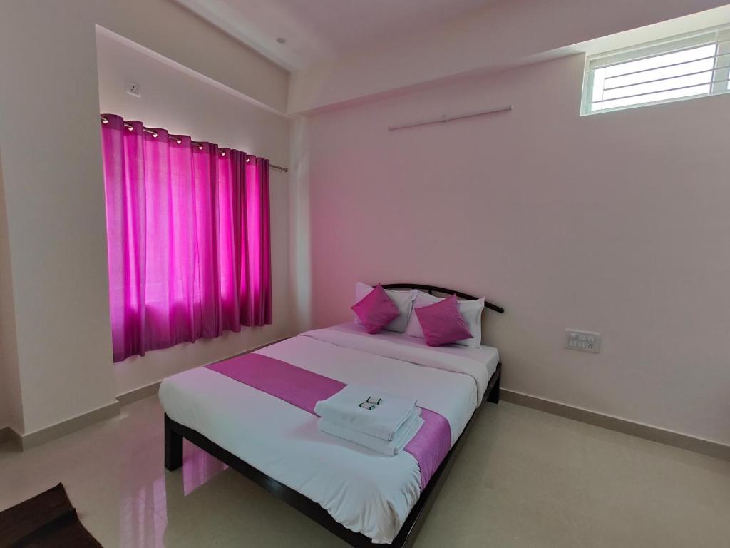 迈索尔Lishan Apartment的一间卧室配有一张带粉红色窗帘的大床