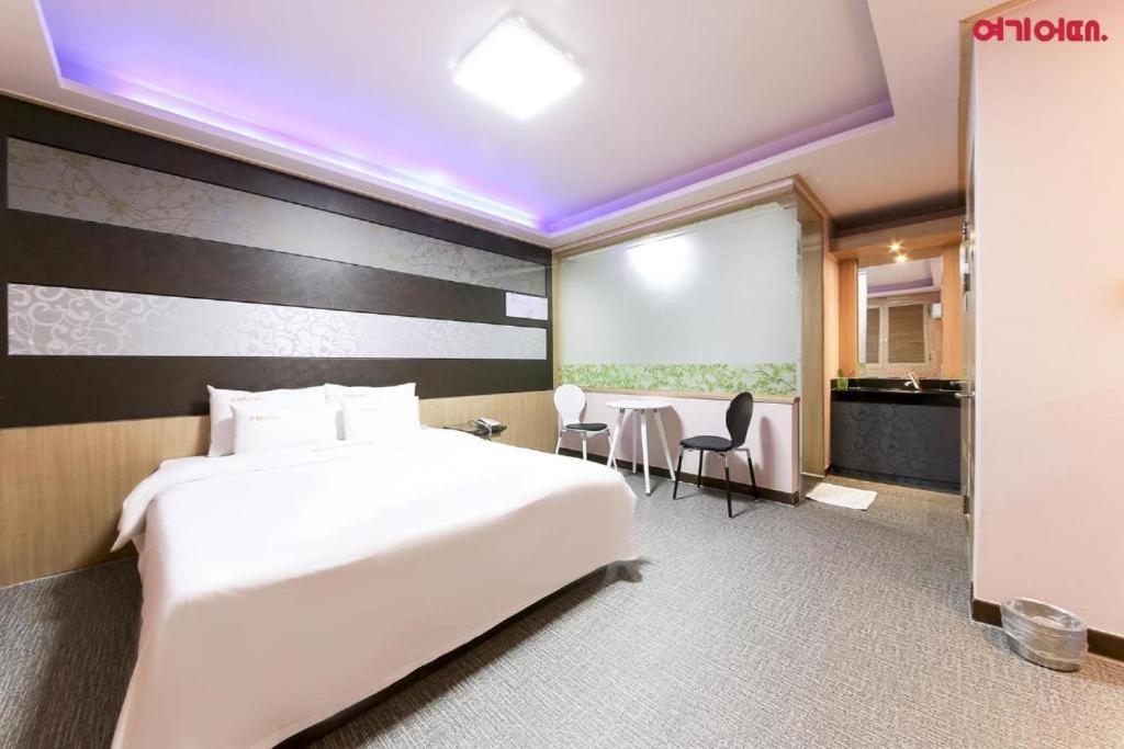 全州市Sharp Hotel Jeonju的酒店客房带一张床、一张桌子和椅子