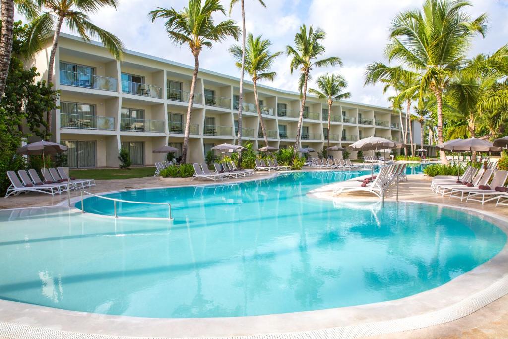 蓬塔卡纳Impressive Premium Punta Cana - All Inclusive的度假村的游泳池,配有椅子和棕榈树