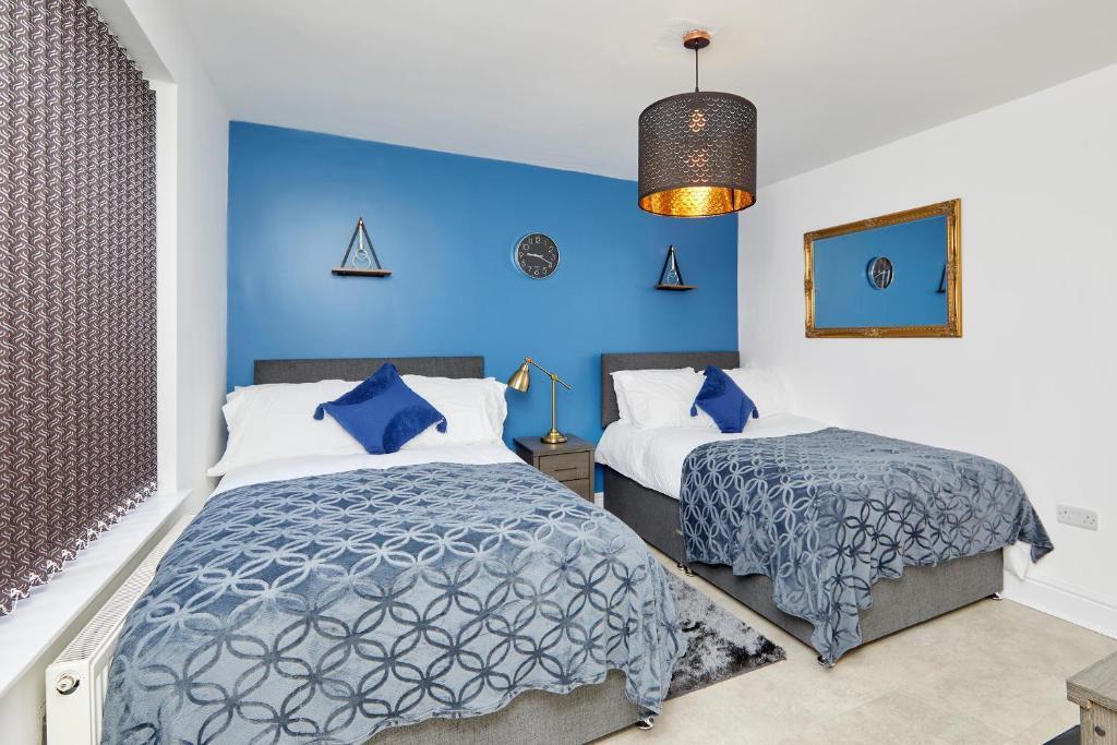 诺丁汉3 Bed Notts City Centre Town House - Free parking的一间卧室设有两张床和蓝色的墙壁