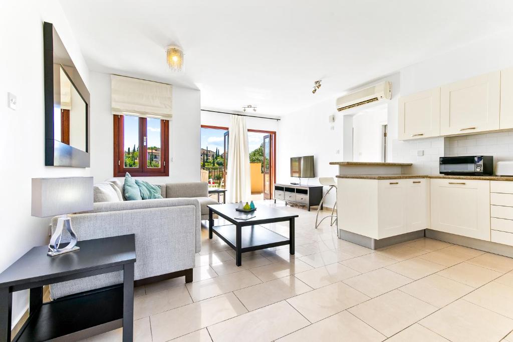 库克里亚2 bedroom Apartment Anatoli with communal pool, Aphrodite Hills Resort的厨房以及带沙发和桌子的客厅。