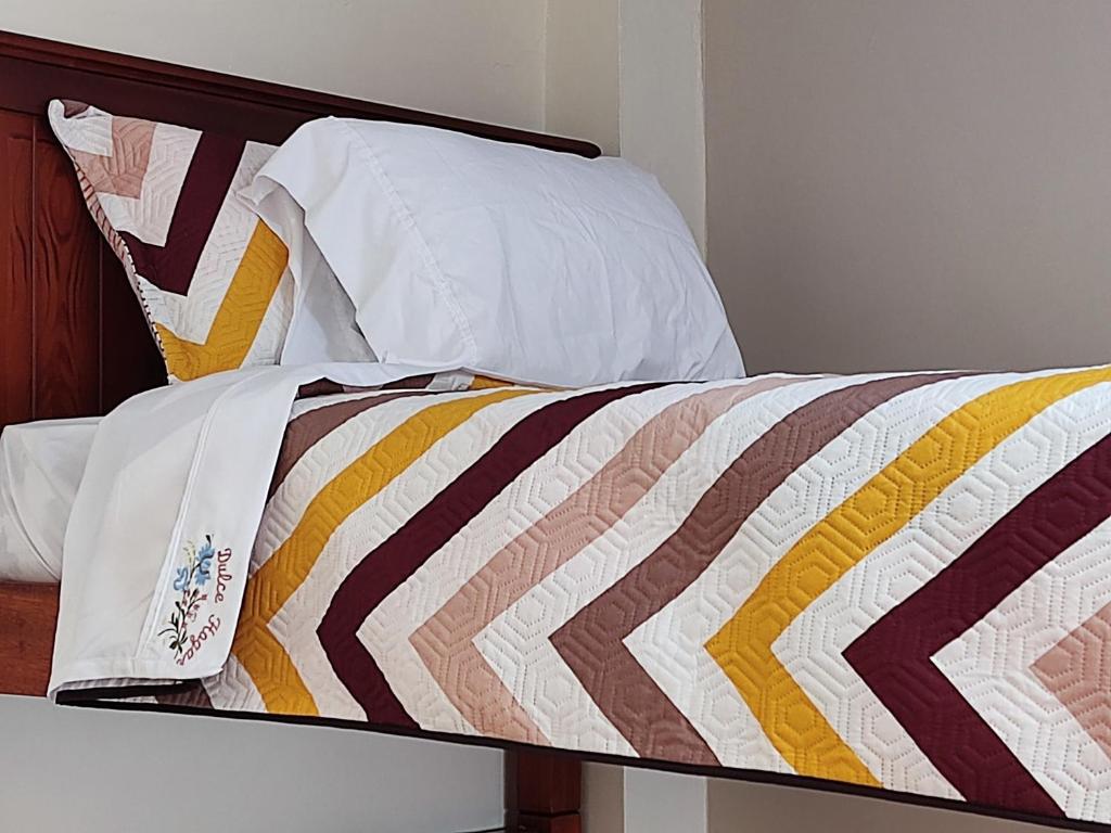 洛哈Dulce Hogar 02的床上配有色彩缤纷的被子和枕头
