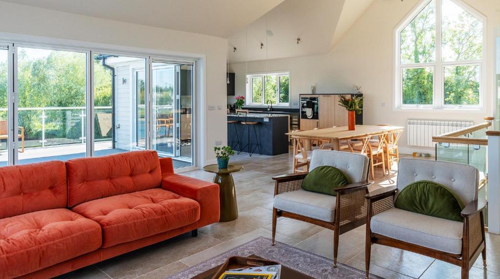 南塞尔尼Gorgeous 4 bedroom Cotswolds home with lake view的客厅配有红色的沙发和椅子