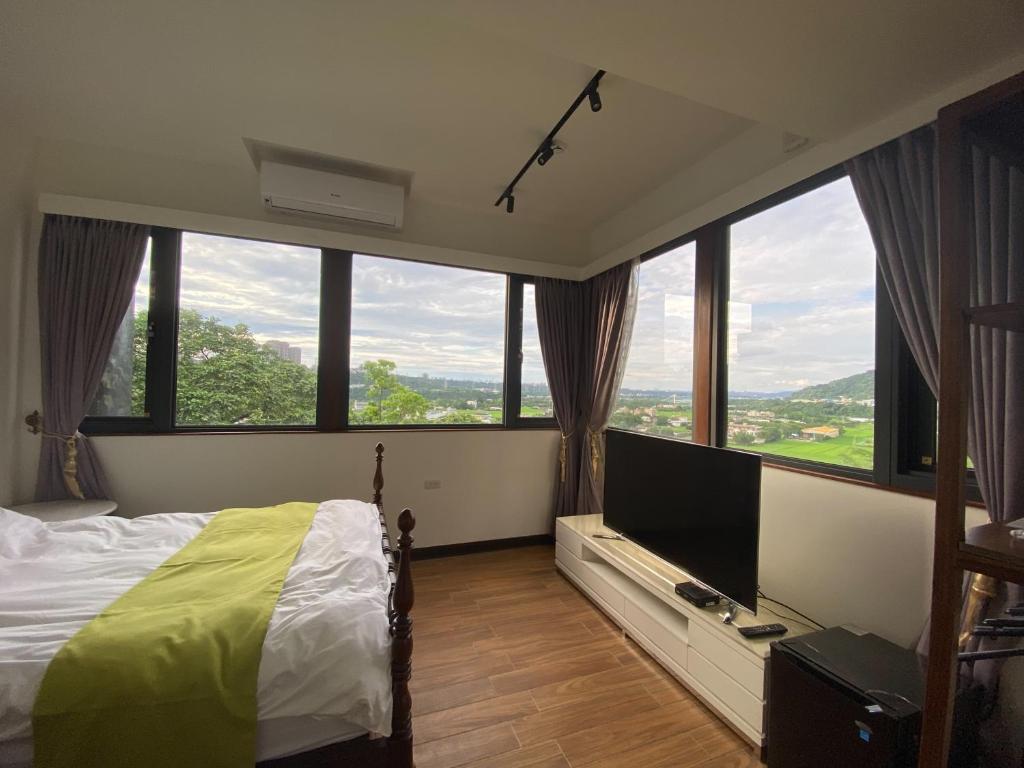 大溪Lemuju樂木居河岸行館的一间卧室设有大窗户、一张床和电视。
