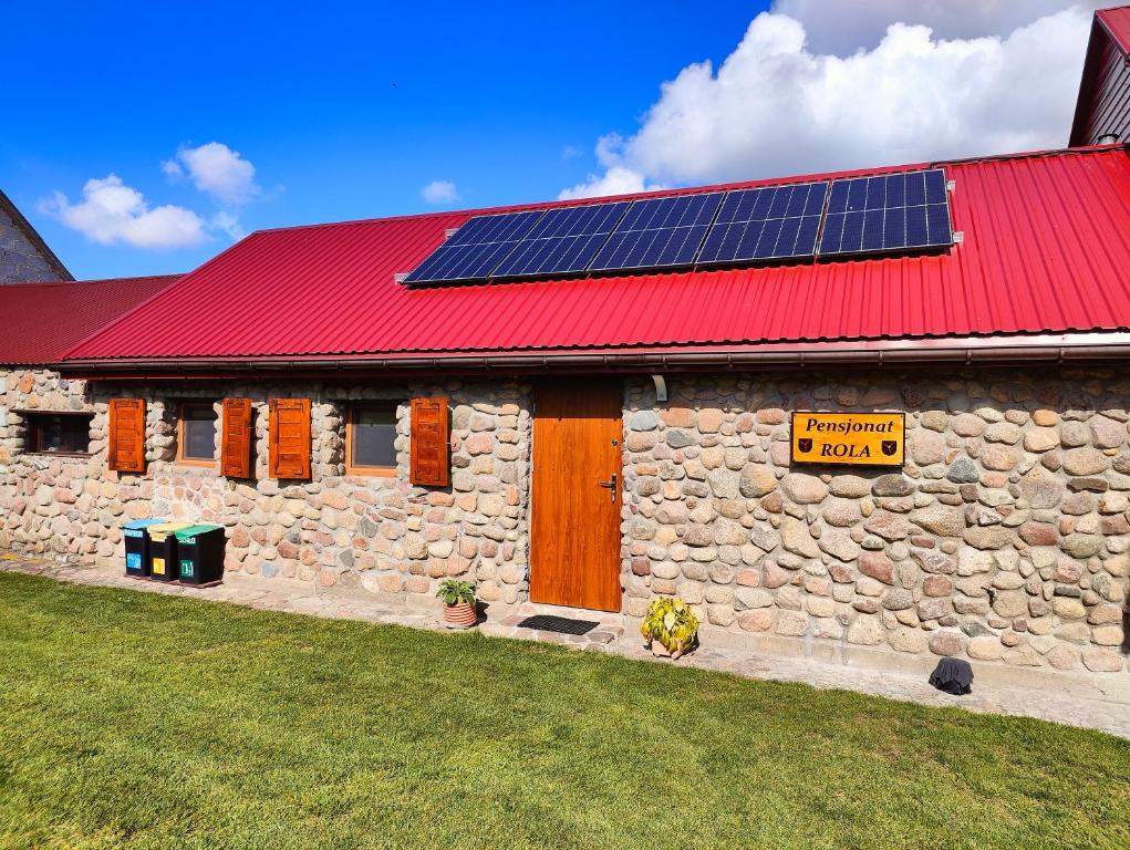蒂科钦Prywatny domek koło Tykocina的一座建筑,上面有红色的屋顶,上面有太阳能电池板