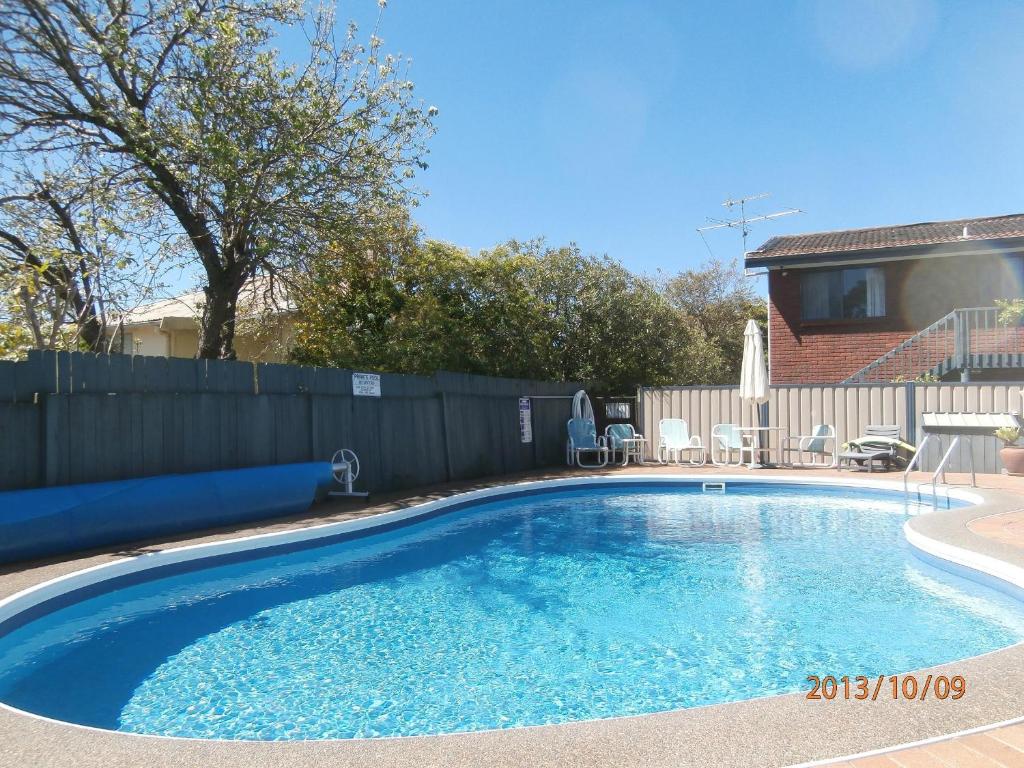 梅林布拉海港之光假日公寓的一个带围栏的院子内的游泳池