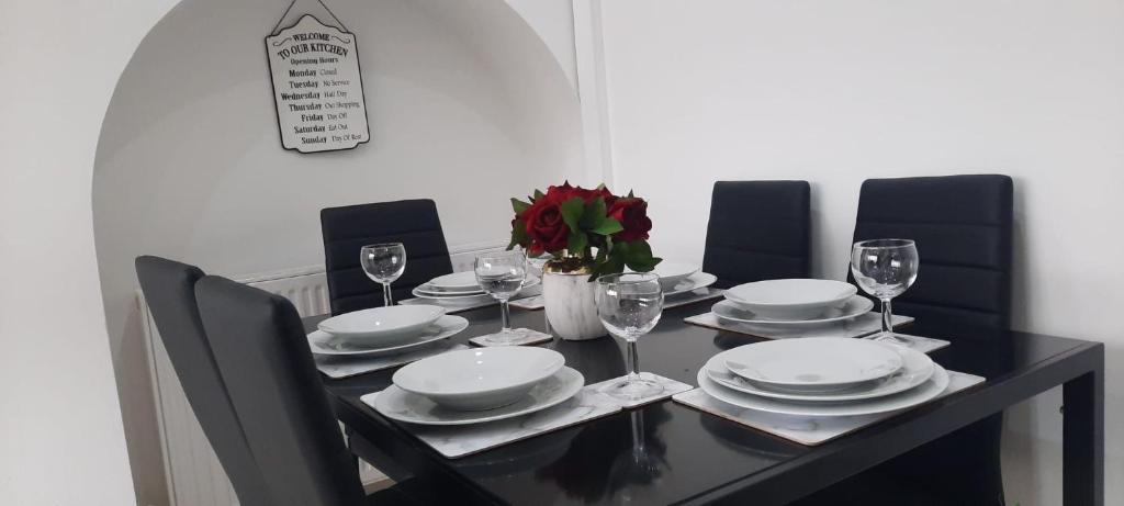 MinworthStylish and homey 3 bedroom house with free parking & Wi-Fi的一张带盘子和酒杯的黑色餐桌