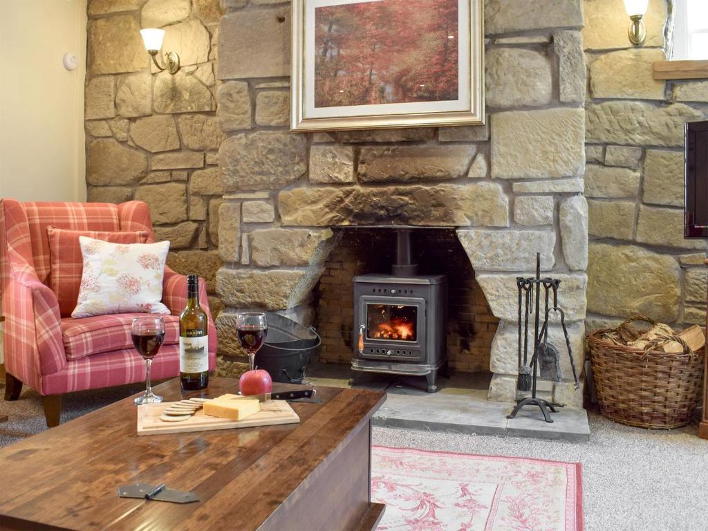 肯莫尔Deuchars Cottage的客厅设有石制壁炉和带酒杯的桌子。