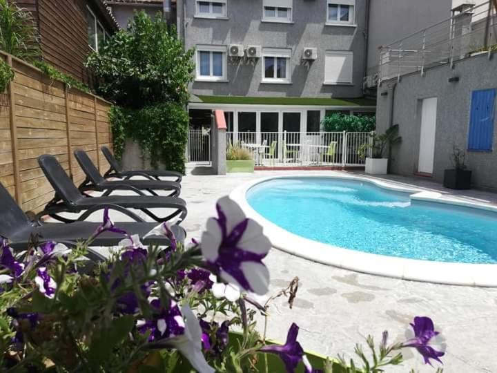 鲁西隆地区卡内Hotel Le Majestic Canet plage的一座带两把椅子的游泳池位于大楼旁