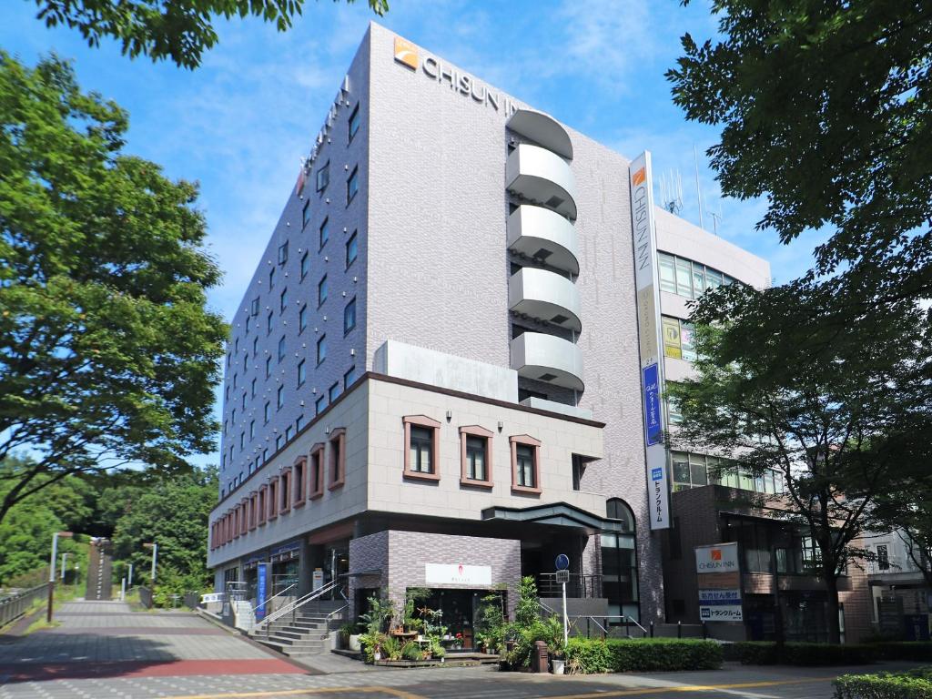横滨Chisun Inn Yokohama Tsuzuki的一座高大的建筑,旁边有一个标志