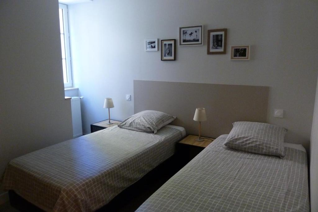 米洛Chez Berni的卧室内的两张床,配有两盏灯和墙上的照片