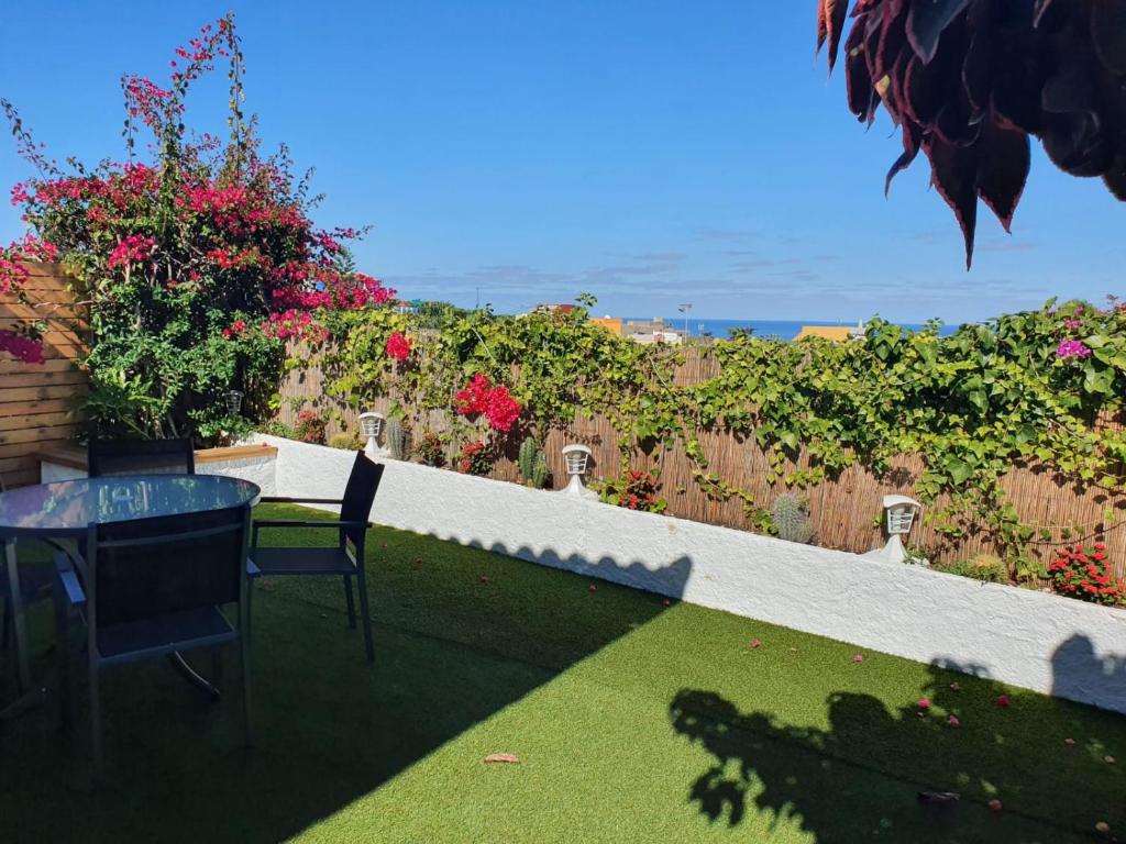拉克鲁斯Cozy and intimate bungalow in Puerto de la Cruz的庭院配有桌椅和鲜花