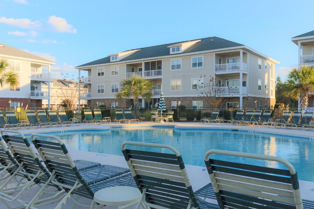 默特尔比奇River Oaks Golf Resort的一座带椅子的大型游泳池和一座建筑