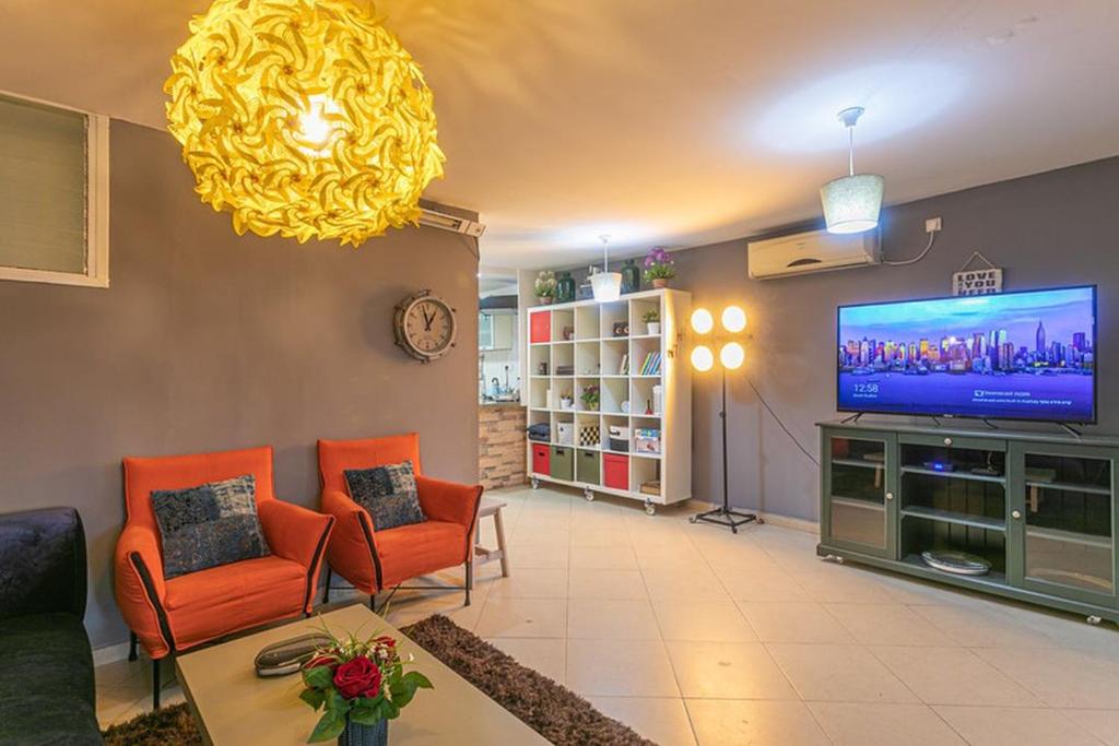 贝尔谢巴The Private House רשת הבית הפרטי的客厅配有橙色椅子和平面电视