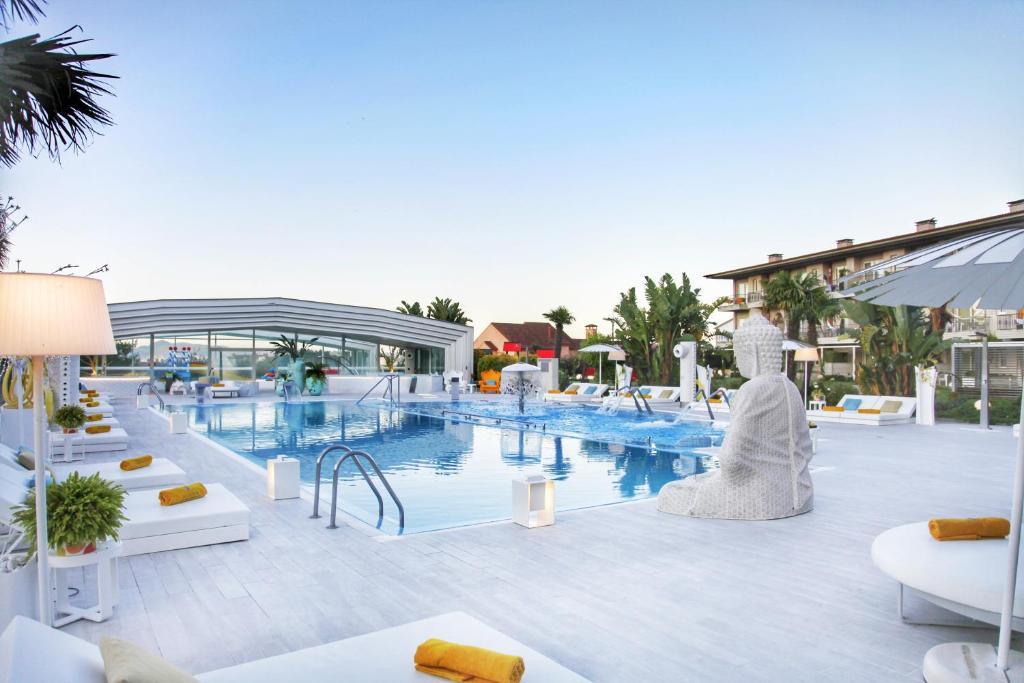桑亨霍Augusta Eco Wellness Resort 4 Superior的一座带白色家具的度假村游泳池以及一座建筑