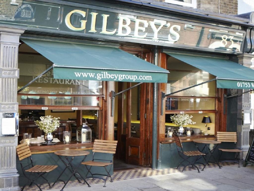 温莎Gilbey's Bar, Restaurant & Townhouse的餐厅前面设有桌椅