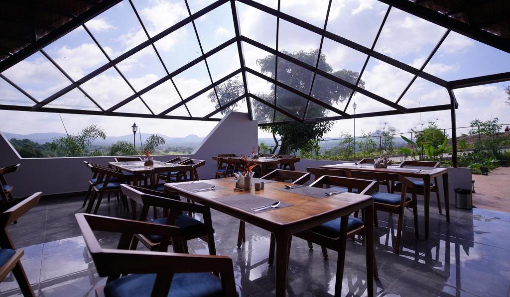RāmanagaramRavishing Retreat Resort的餐厅设有桌椅和大窗户。