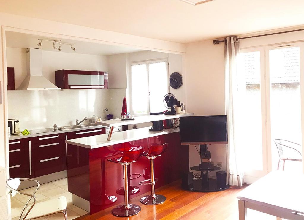 艾克斯莱班Appartement en plein cœur d'Aix-les-Bains的厨房里设有柜台和红色凳子