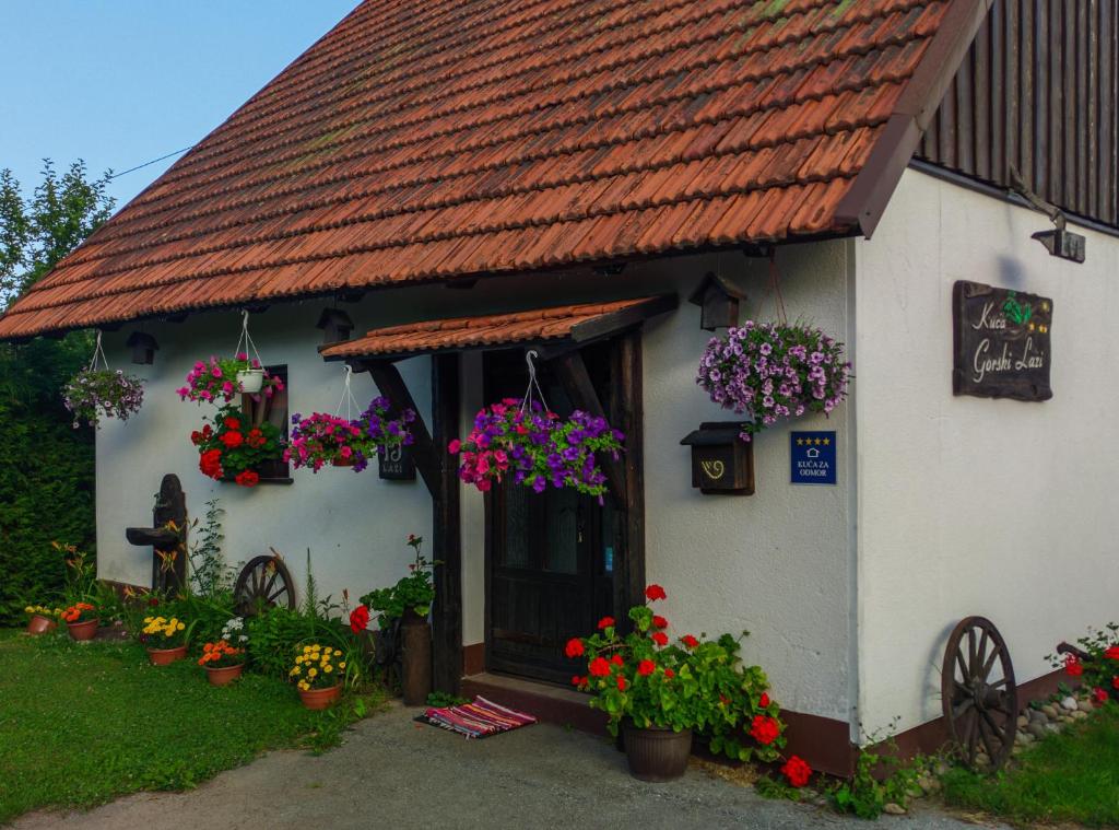 TršćeHoliday Home Gorski Lazi的花卉和植物的小白色房子