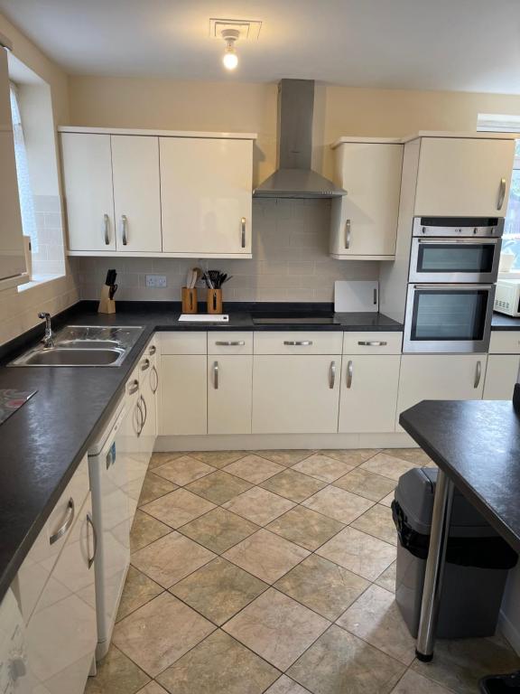曼斯菲尔德Spacious 9 bed house in Mansfield Nottinghamshire的厨房配有白色橱柜和瓷砖地板。