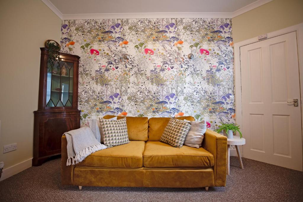 爱丁堡Cosy one bedroom flat in city center的花卉墙面的房间里一张黄色的沙发
