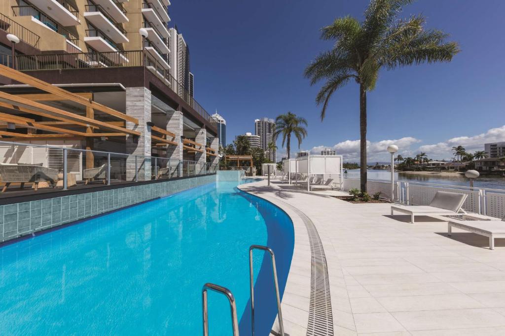 黄金海岸黄金海岸韦伯酒店的棕榈树建筑旁边的游泳池